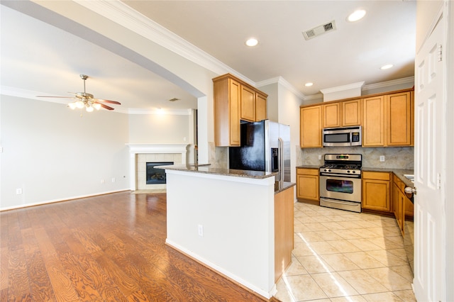 kitchen with ceiling fan, light hardwood / wood-style floors, decorative backsplash, appliances with stainless steel finishes, and ornamental molding