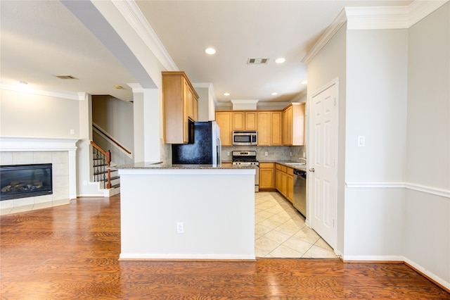 kitchen featuring stone counters, light hardwood / wood-style floors, crown molding, and appliances with stainless steel finishes