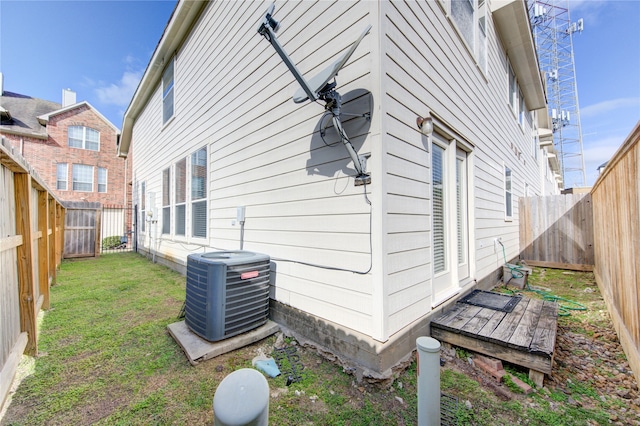 view of side of property featuring central AC unit and a lawn