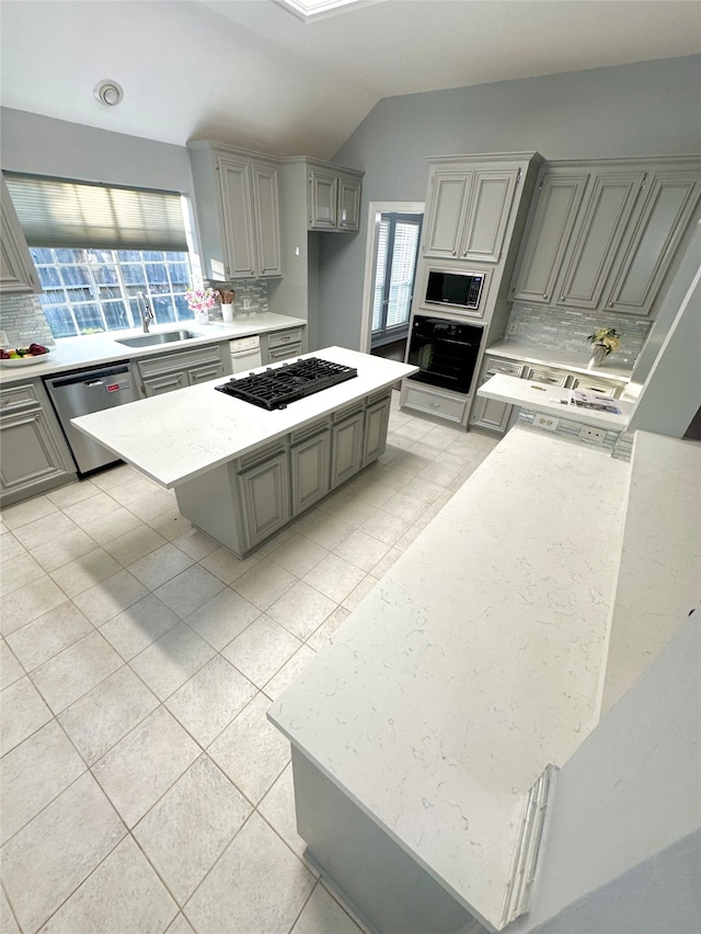 kitchen with sink, stainless steel dishwasher, decorative backsplash, built in microwave, and a kitchen island