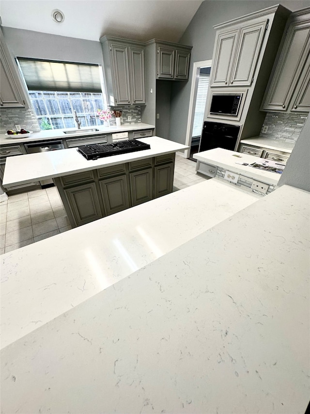 kitchen featuring gray cabinets, decorative backsplash, built in microwave, and gas stovetop