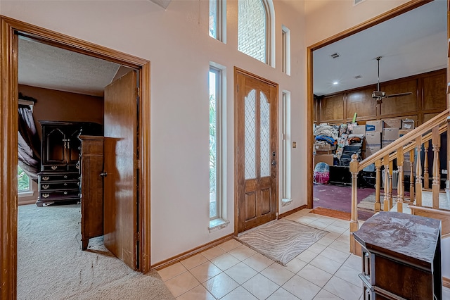 tiled foyer entrance featuring a textured ceiling, ceiling fan, and a healthy amount of sunlight