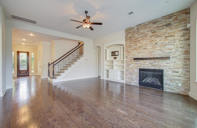 unfurnished living room featuring dark hardwood / wood-style floors, ceiling fan, built in shelves, ornamental molding, and a fireplace