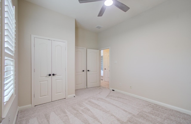 unfurnished bedroom featuring ceiling fan, a closet, and light carpet