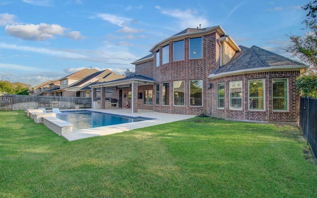 rear view of property featuring area for grilling, ceiling fan, a patio area, and a lawn