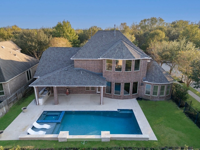 back of house featuring a yard, a patio, and a pool with hot tub