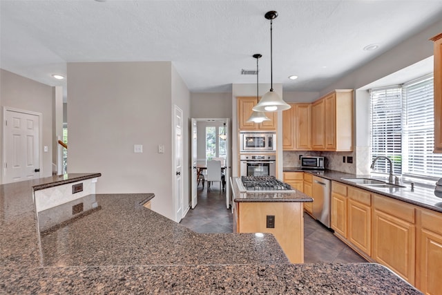 kitchen featuring light brown cabinets, sink, hanging light fixtures, stainless steel appliances, and a kitchen island