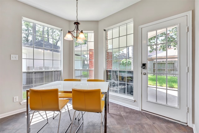 dining area with dark tile patterned flooring and a notable chandelier