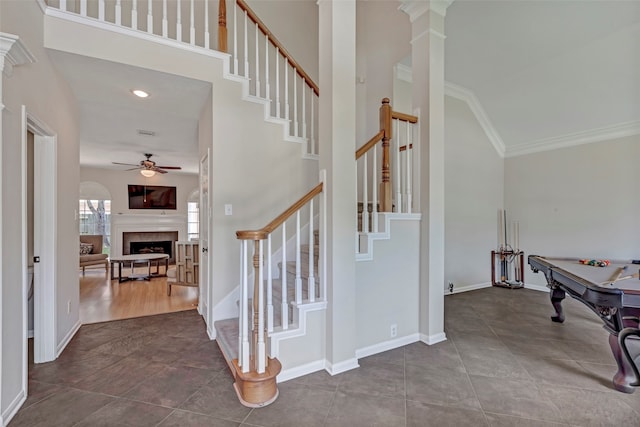 interior space featuring a towering ceiling, ornamental molding, ceiling fan, hardwood / wood-style flooring, and pool table