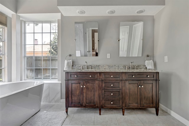 bathroom featuring tile patterned flooring, vanity, and a washtub