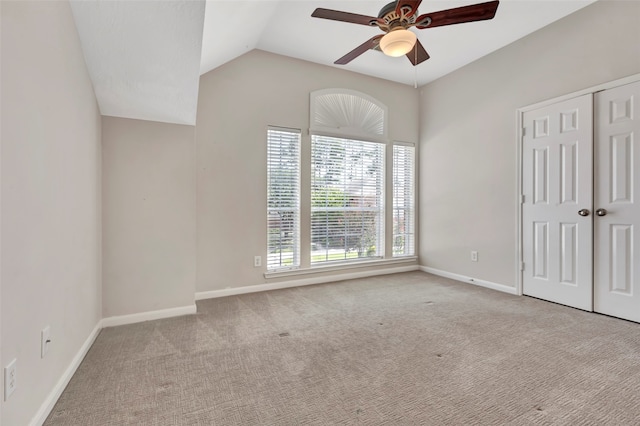 unfurnished bedroom with a closet, light colored carpet, vaulted ceiling, and ceiling fan