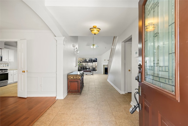 foyer featuring light hardwood / wood-style flooring, ornate columns, ceiling fan, and crown molding