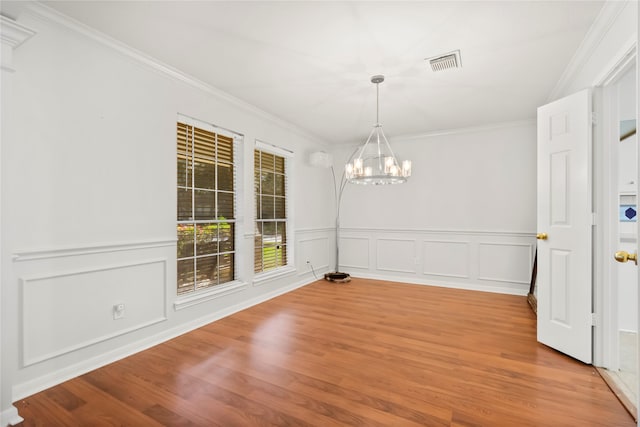 unfurnished dining area featuring crown molding, a chandelier, and light wood-type flooring