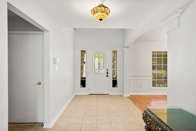 tiled entryway with decorative columns, a wealth of natural light, and crown molding