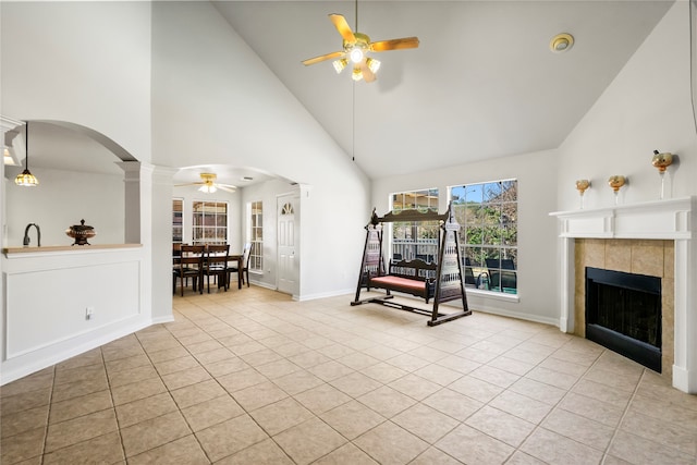 sitting room with ornate columns, ceiling fan, light tile patterned floors, high vaulted ceiling, and a tiled fireplace