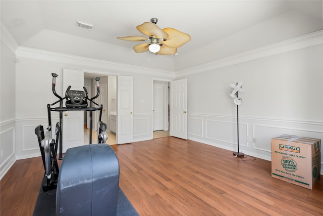 workout room with ceiling fan, wood-type flooring, crown molding, and a tray ceiling