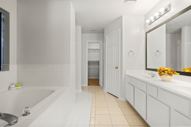 bathroom featuring tiled tub, tile patterned flooring, and vanity