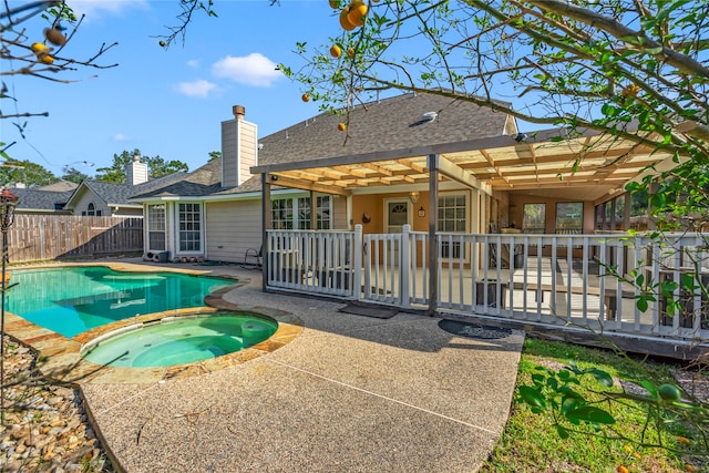 rear view of property featuring a swimming pool with hot tub and a patio area