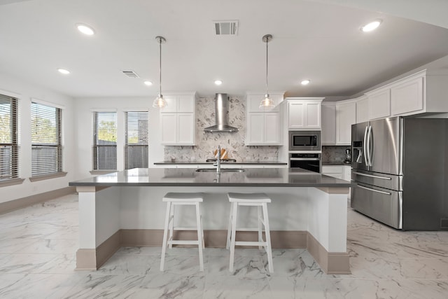 kitchen featuring white cabinets, decorative light fixtures, stainless steel appliances, and wall chimney range hood