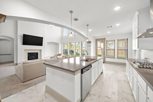 kitchen with white cabinets, sink, wall chimney exhaust hood, an island with sink, and appliances with stainless steel finishes