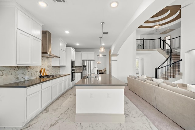 kitchen with white cabinets, decorative light fixtures, and wall chimney range hood