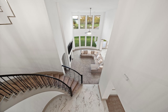 staircase featuring a high ceiling, carpet floors, and ceiling fan