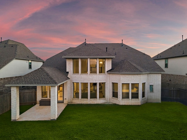 back house at dusk with a yard and a patio area