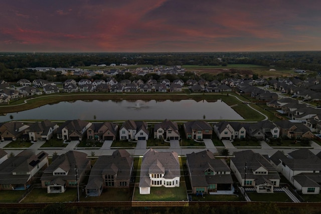 aerial view at dusk featuring a water view