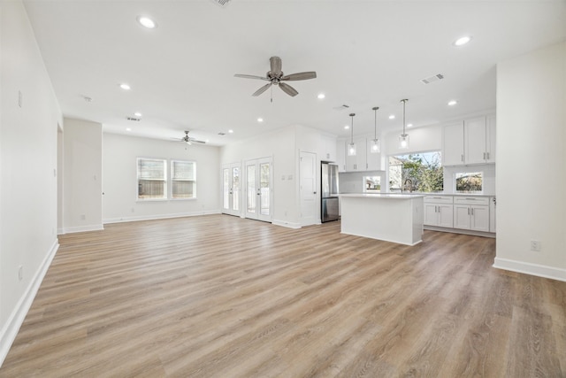 unfurnished living room featuring ceiling fan, sink, a healthy amount of sunlight, and light hardwood / wood-style floors