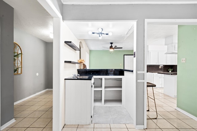 kitchen featuring white cabinetry, ceiling fan, backsplash, a textured ceiling, and light tile patterned floors