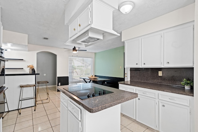 kitchen with white cabinetry, ceiling fan, light tile patterned floors, black electric cooktop, and a kitchen island