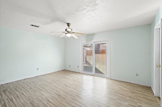 spare room featuring ceiling fan, light wood-type flooring, and a textured ceiling