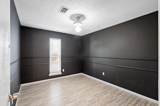 spare room with light wood-type flooring and a textured ceiling