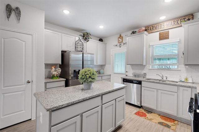 kitchen with sink, light hardwood / wood-style flooring, tasteful backsplash, a kitchen island, and stainless steel appliances