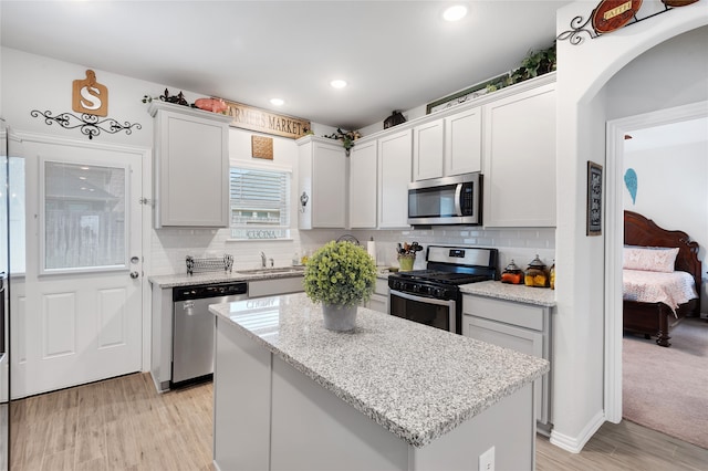 kitchen featuring appliances with stainless steel finishes, light hardwood / wood-style floors, a kitchen island, and sink