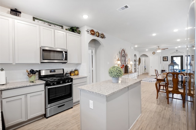 kitchen featuring ceiling fan, light stone countertops, light hardwood / wood-style flooring, white cabinets, and appliances with stainless steel finishes