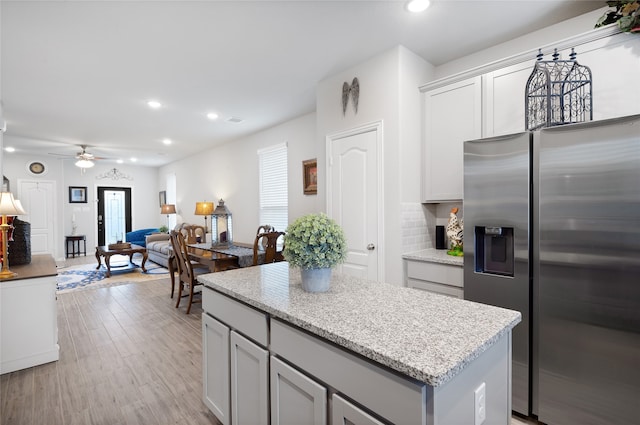 kitchen with ceiling fan, decorative backsplash, a kitchen island, light hardwood / wood-style floors, and stainless steel fridge with ice dispenser