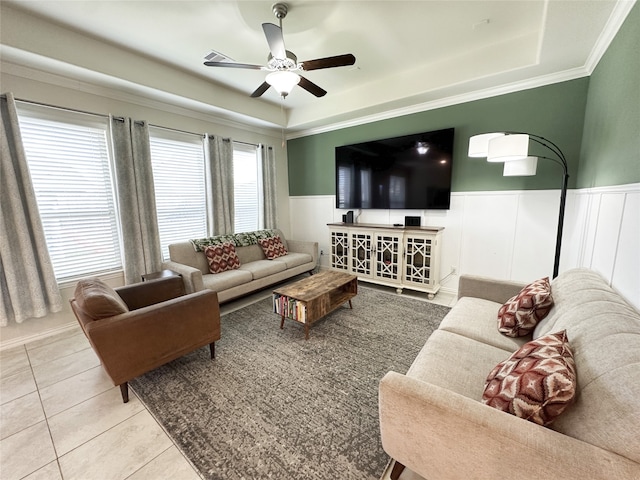 tiled living room with a raised ceiling, ceiling fan, and crown molding