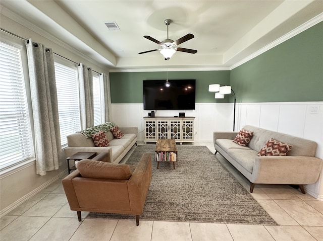 tiled living room featuring a raised ceiling, ceiling fan, and crown molding