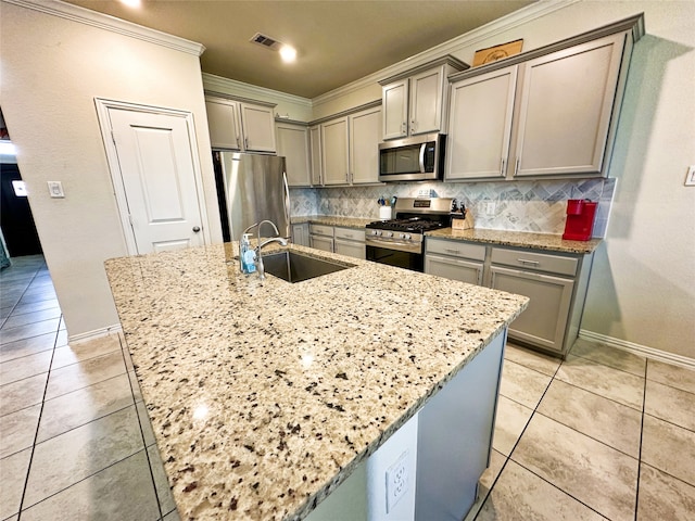 kitchen with light stone countertops, sink, an island with sink, and appliances with stainless steel finishes