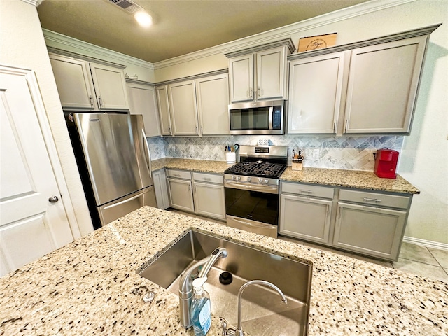 kitchen featuring sink, crown molding, decorative backsplash, light stone counters, and stainless steel appliances