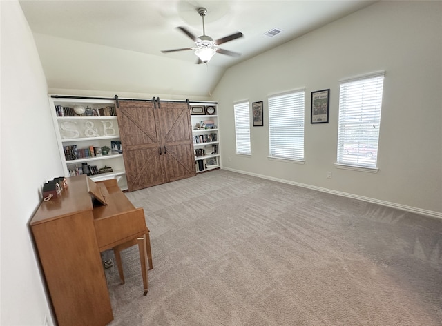 unfurnished office with a barn door, ceiling fan, light colored carpet, and vaulted ceiling