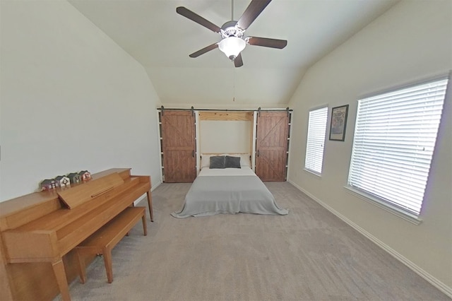 unfurnished bedroom with ceiling fan, a barn door, light colored carpet, and vaulted ceiling