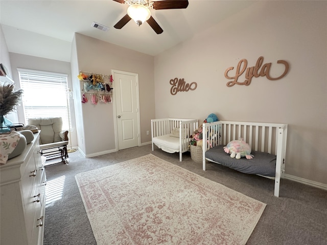 carpeted bedroom with ceiling fan and a crib