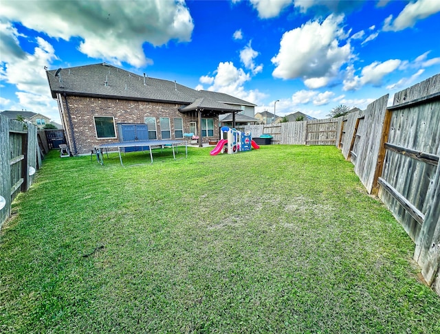 view of yard featuring a playground and a trampoline