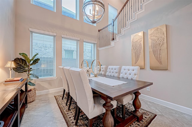 dining space with a high ceiling, light tile patterned flooring, and a chandelier