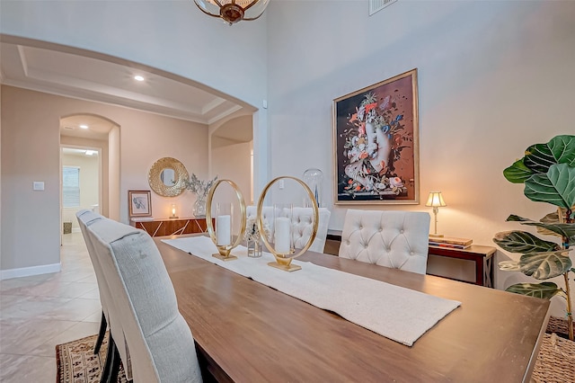 tiled dining room featuring a tray ceiling and a high ceiling