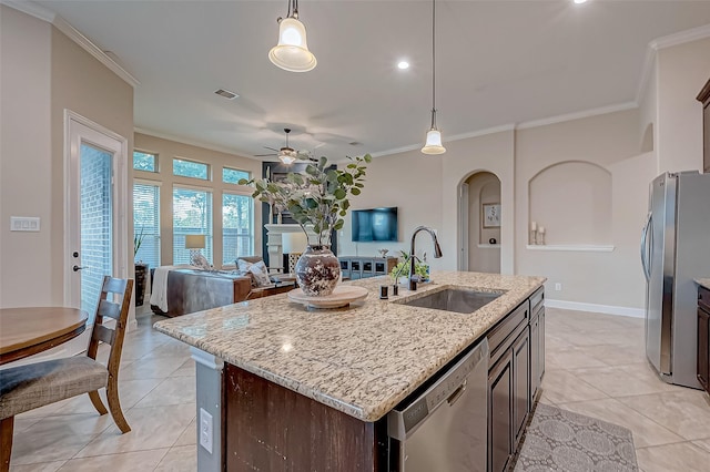 kitchen with sink, stainless steel appliances, dark brown cabinetry, a center island with sink, and decorative light fixtures