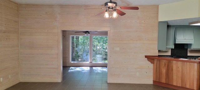 kitchen featuring ceiling fan, wood walls, and green cabinetry