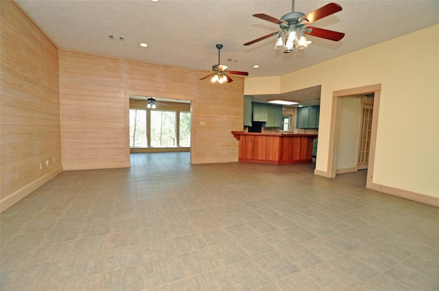 unfurnished living room featuring recessed lighting, wooden walls, visible vents, baseboards, and light floors